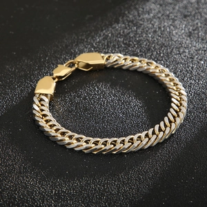 Detail of two-tone gold and silver Cuban link bracelet with geometric buckle on dark background