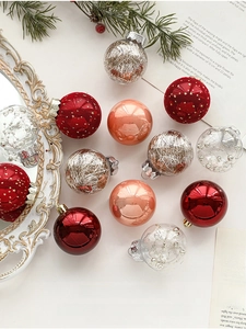 Close-up of assorted 5cm red and rose gold Christmas baubles with glitter and lace details