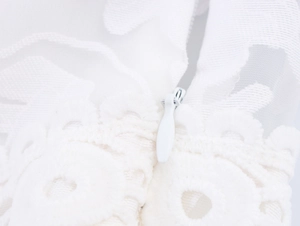 Detailed macro shot of a white invisible zipper on an embroidered lace and mesh dress