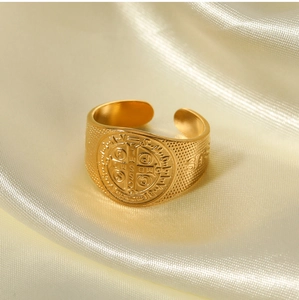 Close-up of vintage 18K gold plated St. Benedict medal ring on champagne silk background