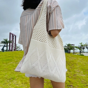 Outdoor shot showing back view of woman carrying large off-white knit cotton tote bag