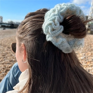 Outdoor shot of mint green ruffled knit hair scrunchie worn on a beach background