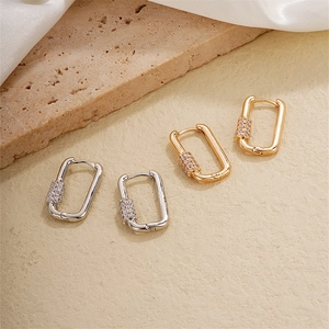 Minimalist gold and silver square hoop earrings with cubic zirconia set on stone background