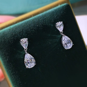 Macro view of teardrop high-carbon diamond drop earrings on dark green velvet