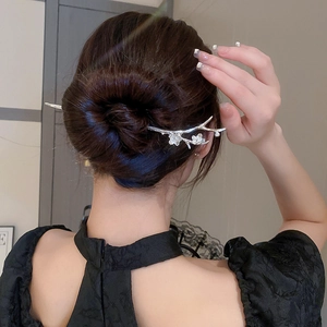 Close-up of a silver plum blossom hair pin with delicate floral detailing on dark hair