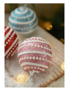 Detail of glitter Christmas balls with faux pearl ribbons and warm festive lighting