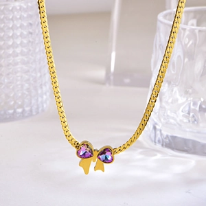 Golden necklace with purple crystal heart bow pendant on a white marble background