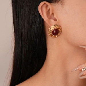 Detail of vintage gold textured round stud earrings with a deep red resin center