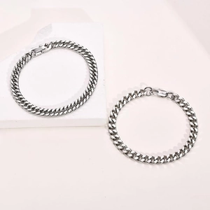Detailed macro view of silver Cuban link bracelets with lobster and fold-over clasps