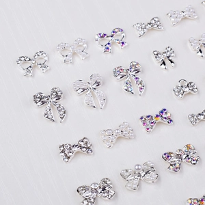 Detailed view of silver bow nail art charms with sparkling rhinestones and pearls