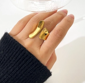 Detailed close-up of chunky gold-plated irregular geometric open ring on finger