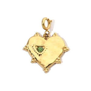 Detail of a heart pendant with green gemstone and radiating spikes in golden finish