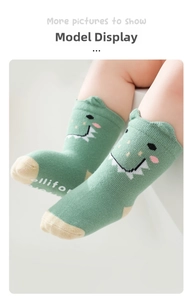 Detail showing green baby socks with 3D dinosaur ears and non-slip silicone grip soles