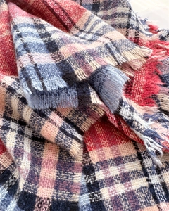 Close-up of woven plaid scarf texture with soft fringes and colorful tartan pattern