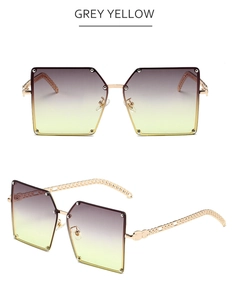 Macro detail of square rimless sunglasses with gold chain temples and grey yellow lenses