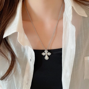 Close-up of cross pendant with mother of pearl finish and micro diamonds on model