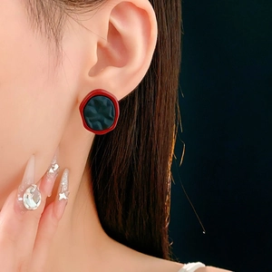 Gros plan de boucles d'oreilles rétro avec bord rouge et texture de résine plissée noire