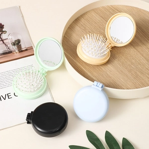 Set of four portable folding round hairbrushes with built-in mirrors in assorted pastel colors