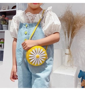 Close-up of child yellow daisy round crossbody bag with floral shirt and denim overalls