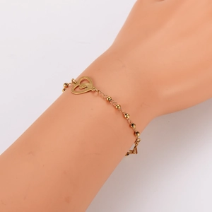 Golden bead chain bracelet with hollow heart pendant shown on a model wrist