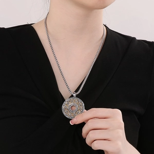 Close-up of vintage silver round pendant with infinity gold accents on woven chain