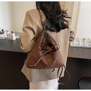 Detail of dark brown faux suede tote bag with drawstring bow and leather strap on a model