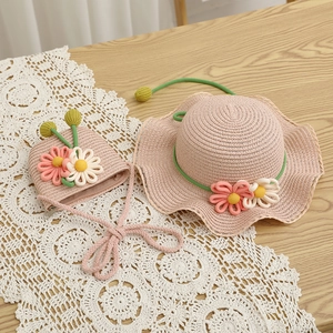 Detail of pink straw sun hat and matching floral bag set on a white lace tablecloth