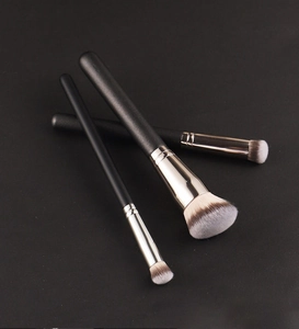 Close-up of three professional makeup brushes with silver ferrules and soft gradient bristles