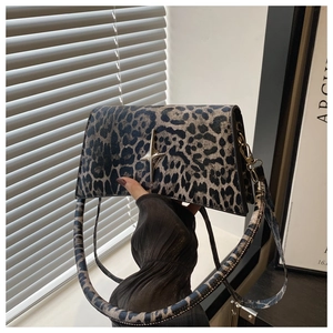 Gros plan du sac bandoulière léopard avec un fermoir métallique doré en forme d'étoile
