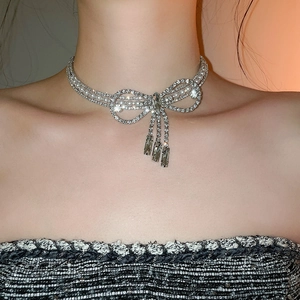 Close-up of sparkling bow necklace with rhinestones, pearls and short tassels on a model