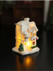 Close-up of a resin Christmas snow house with warm LED lighting and a 'GIFT' inscription