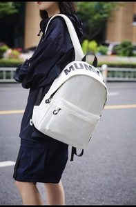 Close-up of white canvas backpack with black MUM print and adjustable straps