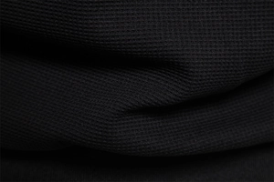 Close-up of black waffle texture knit fabric showing detailed square pattern on jacket