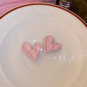 Dettaglio degli orecchini rosa a forma di cuore con finitura a trama lavica irregolare