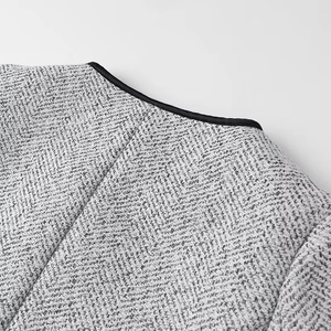 Detail of grey tweed jacket showing herringbone texture and black neckline piping