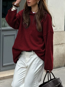 Street style view of a red loose-fit long sleeve hooded knit sweater with lapel collar