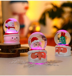 Macro view of Christmas crystal balls with snowman and Santa resin base and glowing lights
