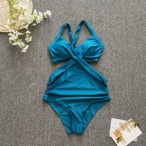 Close-up of teal one-piece swimsuit featuring cross-neck design and ruched details