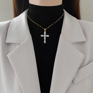 Collier croix élégant en acier titane doré avec pavé de diamants sur un modèle femme