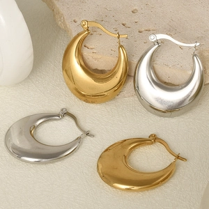 Macro detail of gold and silver U-shaped chunky hoop earrings on stone background