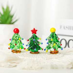 Three handmade glass mini Christmas trees with colorful ornaments on a knit mat