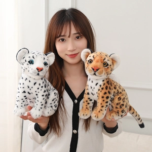Close-up of cute plush snow leopard and leopard dolls held by a model for size comparison
