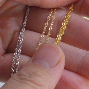 Detail view of gold and silver twist rope chains showing various thickness on skin