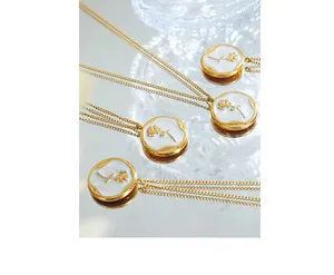 Detailed macro view of a gold-plated rose enamel pendant necklace on a reflective surface