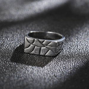 Macro shot of rectangular men's steel ring with irregular cracked geometric textures