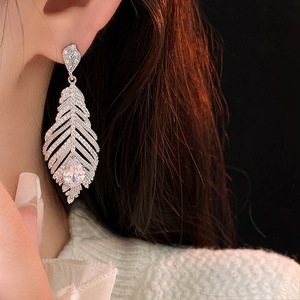 Détail de boucles d'oreilles plume en argent avec des pierres de zircon blanc brillant