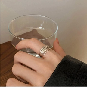 Detail of minimalist multilayer silver rings on hand showing sleek metallic texture