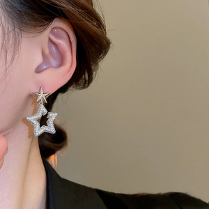 Detail of silver star earrings featuring sparkling cubic zirconia on a female model