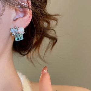 Macro shot of a geometric silver earring with blue gemstone, pearl, and inlaid diamonds