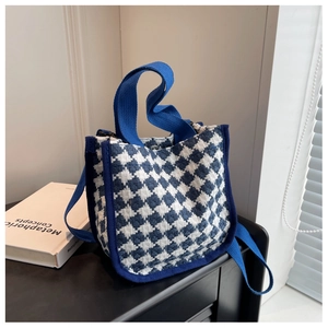 Detail of blue and white houndstooth canvas handbag with webbing handles on a table